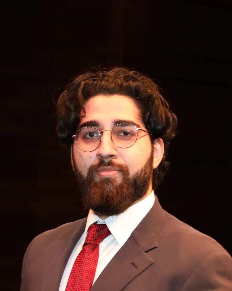 Husaam Ateeq in a dark suit and red tie
